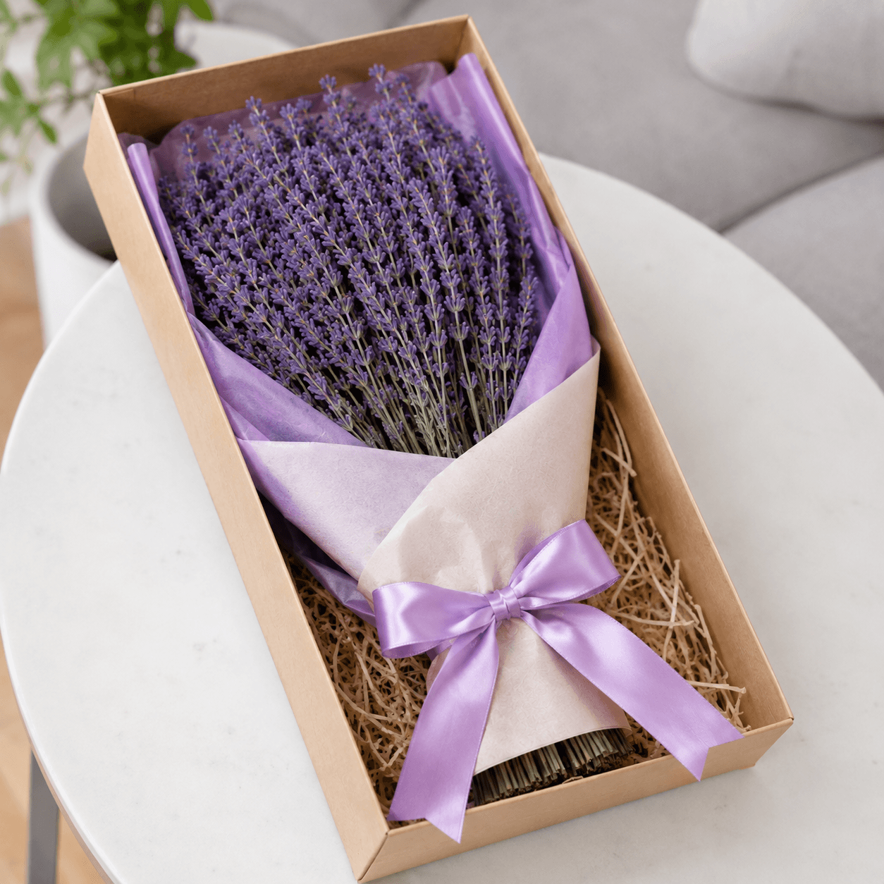 Bouquet of lavender in a box with a purple ribbon on a white surface.