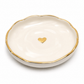 White dish with gold rim and heart-shaped gold emblem on a white background
