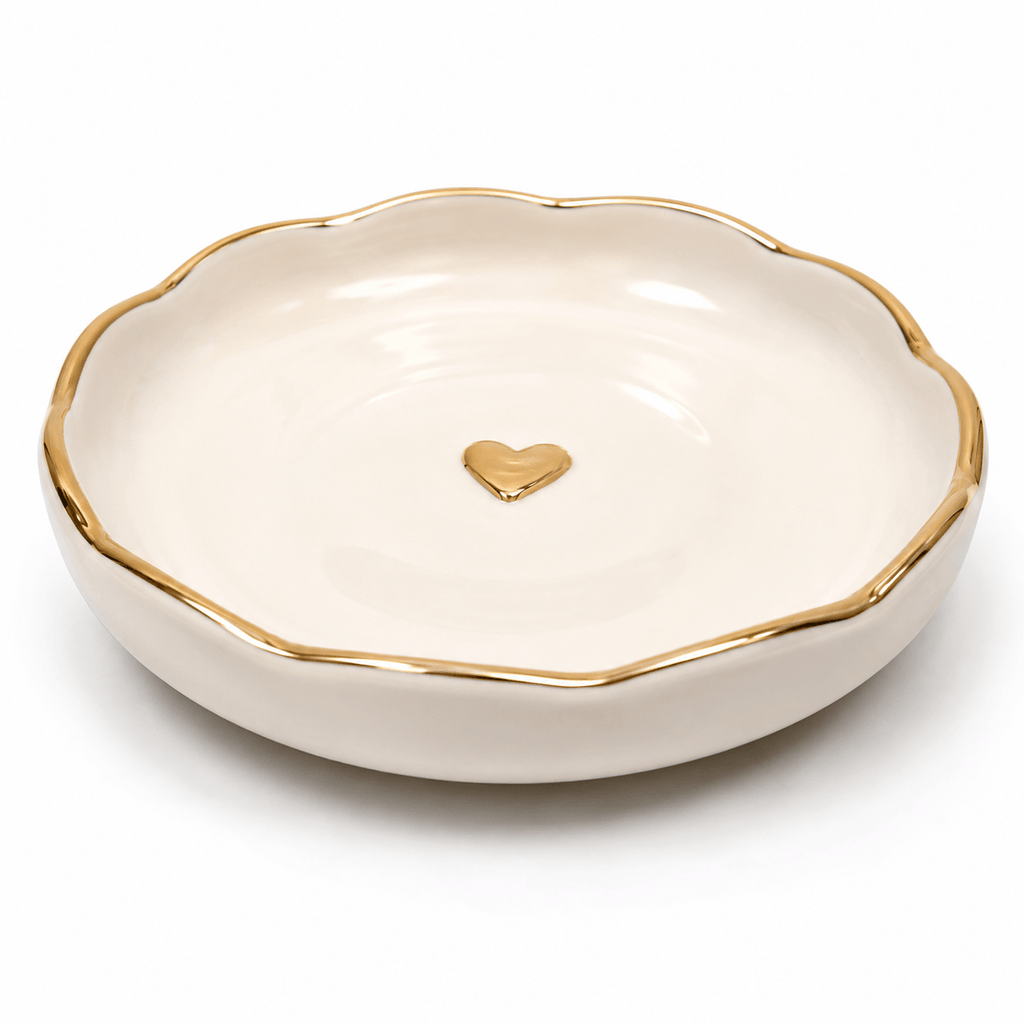 White jewelry dish with gold rim and heart emblem on a white background