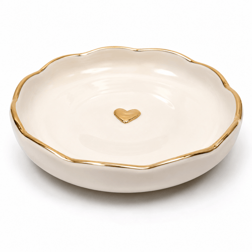 White jewelry dish with gold rim and heart emblem on a white background
